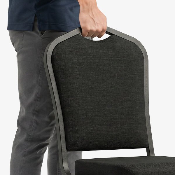Person lifting banquet chair using integrated handhold in chair back