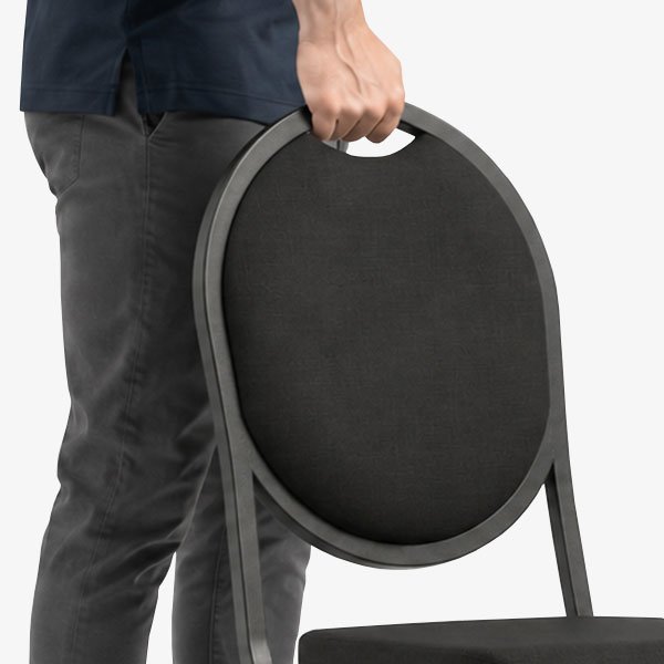 Person lifting banquet chair using integrated handhold in chair back