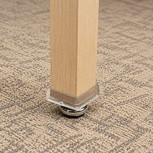 Close-up of a nickel plated rocker glide on an aluminum hospitality chair resting on patterned carpet.