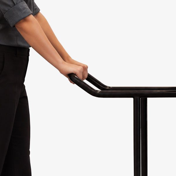 Hospitality employee gripping the extended push handle of the CM-5 Chair Mover transporting stacked commercial chairs.