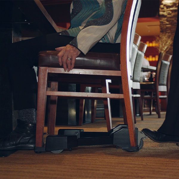 Chair Caddie retrofit installed on a commercial hospitality chair to improve seated mobility and accessibility.